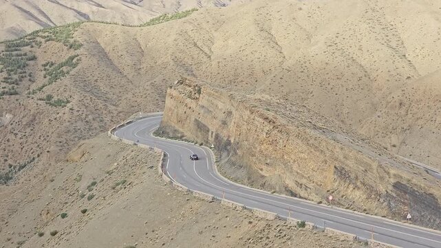 Car rounding the S-curve below a rock buttress on the High Atlas pass at Tizi n'Tichka, Morocco