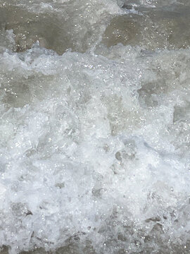 Foamy ocean waves breaking on shallow sand, wave motion, coastal texture, sea foam.