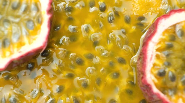 Passion fruit halves rotating slowly over background of juicy pulp, copy space for text