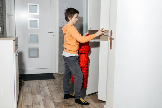 Boy opening closet door to hang red coat
