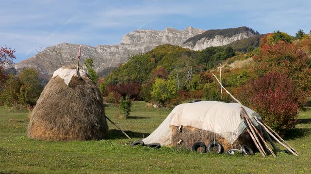 Rural countryside of Montenegro with large haystacks in front of a mountain panorama