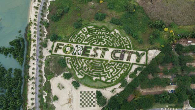 Aerial view of the Forest City maze garden with lush green hedges, a checkerboard pattern area, and surrounding coastal vegetation in Gelang Patah, Johor Darul Ta'zim, Malaysia.