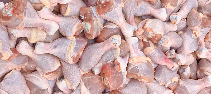 Large quantities of raw chicken legs with the skin still attached. These fresh chicken legs are prepared for wholesale or retail sale.