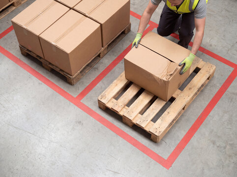 Worker moves damaged carton into warehouse quarantine zone
