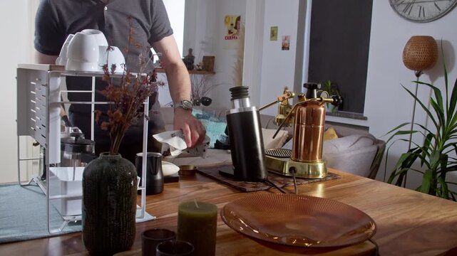 Grinding fresh coffee beans in a modern, sleek single dose grinder, and tamping the ground coffee, on dark hardwood table, in bright, modern, stylish decorated European apartment