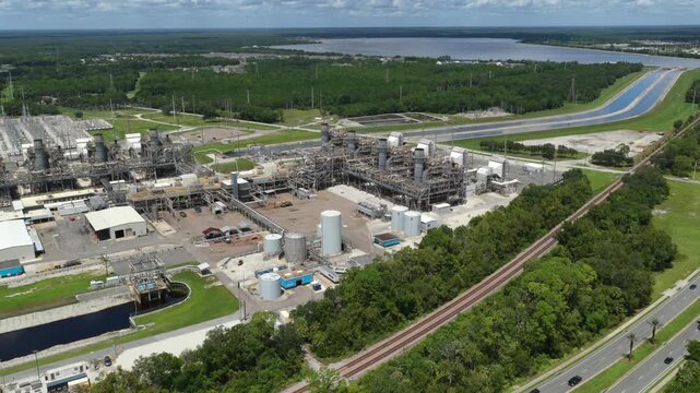 Aerial view of FPL Sanford Power Plant with industrial infrastructure, storage tanks, and railway tracks surrounded by lush green vegetation in DeBary, Florida, United States.