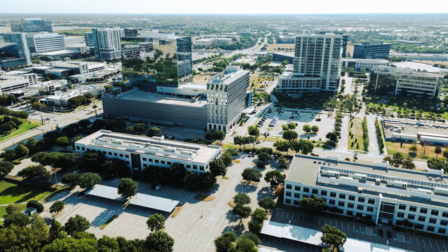 Glazed office facades overlook active corporate thoroughfares near Dallas North Tollway ramps. Expansive business plazas blend with distant suburban horizons, Frisco, Texas