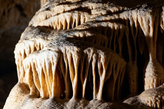 Stalactite formations in a cave with layered rock structures and natural lighting