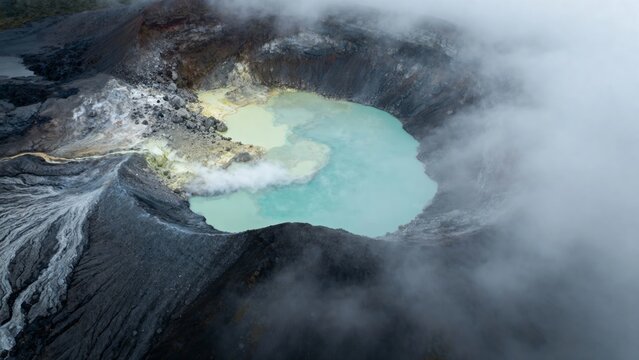 Aerial view of a volcanic crater lake with turquoise water and surrounding steam
