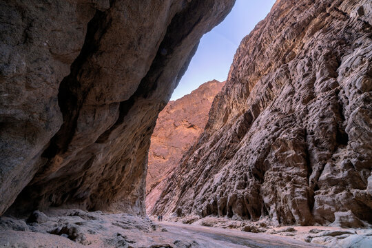 Wide low-angle view of massive towering granite canyon walls with dramatic textured rock surfaces in Tayyib Al Ism, Tabuk