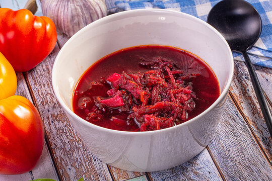 Bowl of borsch with shredded beets and vegetables on rustic wooden table