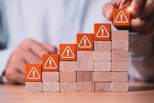 Risk management concept showing increasing warning signs on rising steps as a business professional identifies threats and manages growing risks through assessment, prevention and strategic planning.