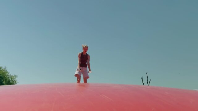 Girl does a handstand on a trampoline outdoors summer slow motion