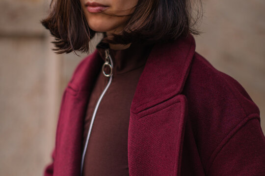 Stylish woman walking through the city in a trendy burgundy wool coat, elegant autumn fashion and modern urban street style