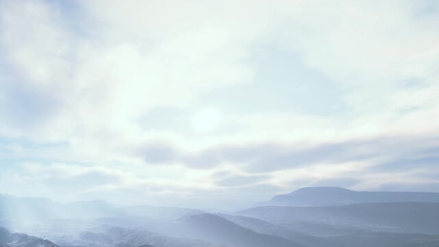 Bright clouds hover over distant mountains during the day. The scene captures the vast landscape and soft light, creating a sense of openness in nature.