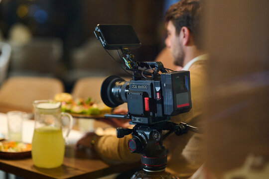 Videographer Filming Food In Restaurant With Professional Cinema Camera On Tripod During Dinner Shoot