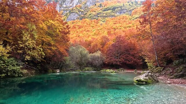 Oko Skakavice, the Blue Eye of Montenegro surrounded by colorful foliage in red, yellow and orange in autumn