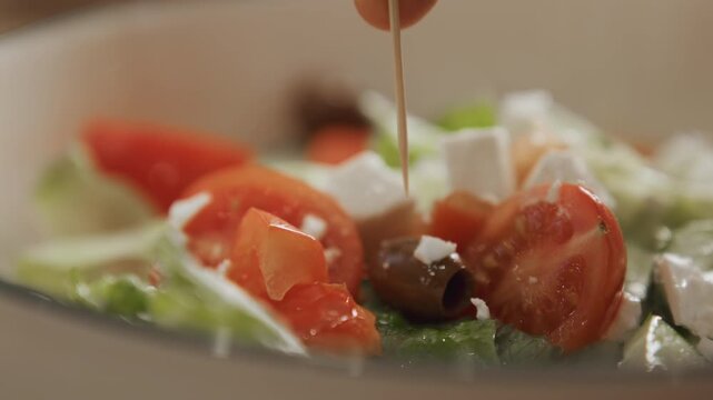 Close up of fresh salad ingredients including tomatoes olives and feta cheese as olive oil is drizzled over them. scene focuses on vibrant textures details like juicy tomato slices crumbled