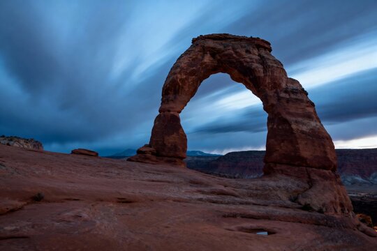 Delicate Arch at twilight with dramatic sky and desert landscape