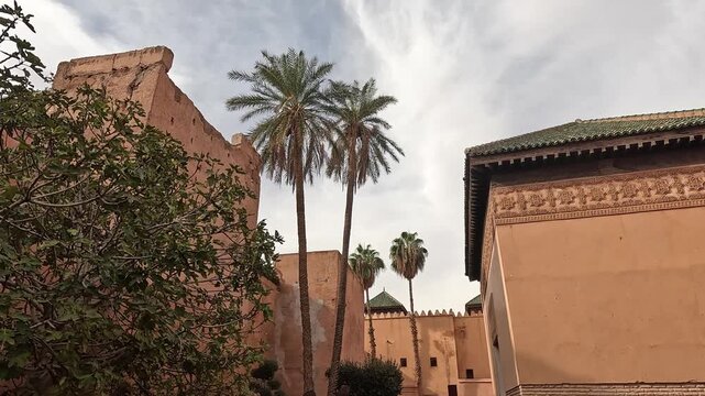Date palms between pise walls and the carved green-roofed mausoleum, Saadian Tombs, Marrakech, Morocco, dusk