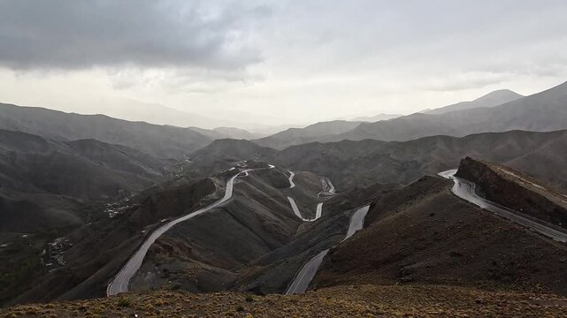 Winding switchback road descending the Tizi n'Tichka pass in the High Atlas, Morocco, hazy overcast day