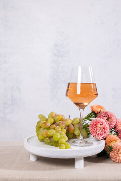Rose wine glass with fresh green grapes and pink flowers