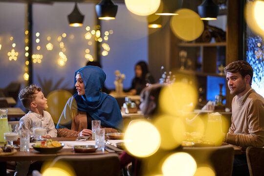 Multicultural Family Dining Together in Cozy Restaurant With Festive Lights and Warm Conversation