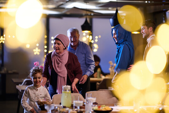 Multi-Generational Muslim Family Celebrating Festive Dinner Together With Warm Lights And Smiles
