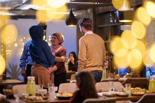 Family Reunion and Warm Greeting Between Women in Hijab at Cozy Holiday Dinner Party