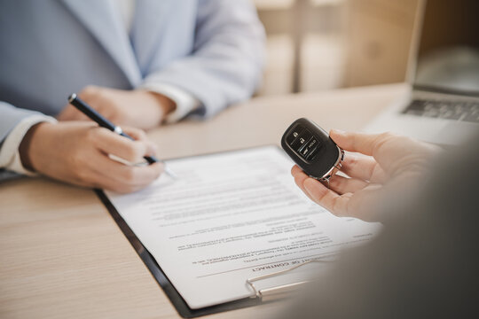 close up shots hands of client signing car lease form.