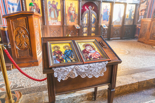 Framed religious icons displayed on a wooden stand in an Orthodox church interior.