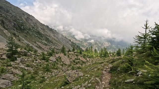 Hiker on rocky trail below Colle della Gianna, Monviso massif, Cottian Alps, Valle Po-Val Pellice divide, Piedmont, Italy