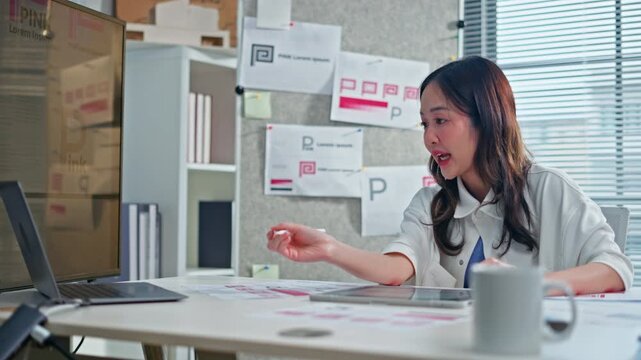 Asian graphic designer showing logo design concept on digital tablet during video call meeting with client,representing creative branding, online presentation,corporate business and online technology