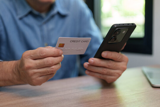 Asian man  holds a credit card and smartphone for secure mobile payment, representing digital banking, identity verification, authentication, online transactions and financial security technology.