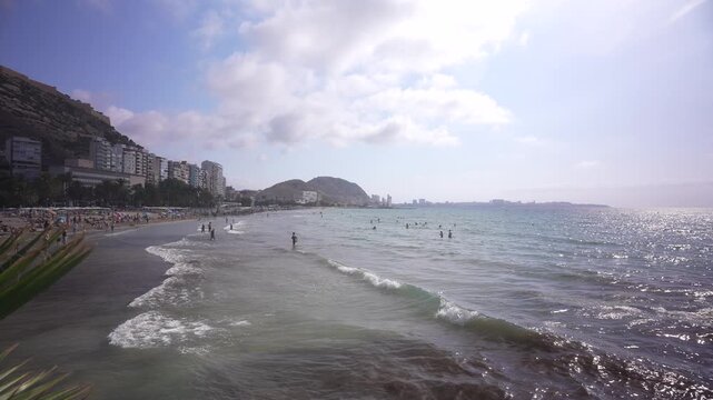 View of sea and public beach on Explanada of Spain and Castillo de Santa Barbara in background on a sunny day, Alicante, Costa Blanca, Spain