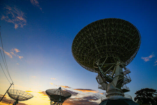 Radio telescope array at sunset, large satellite dish antennas against colorful twilight sky