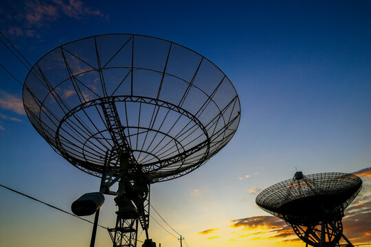 Radio telescope array at sunset, large satellite dish antennas against colorful twilight sky