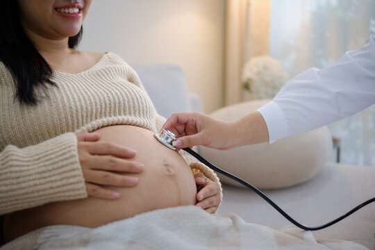 Healthcare professional checking a pregnant woman's belly with a stethoscope.