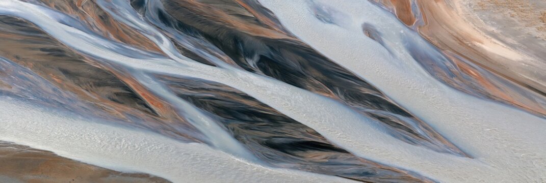 Sinuous tidal channels on sandy flats, aerial view with abstract water patterns