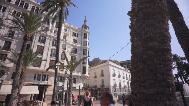 View of people on Explanada of Spain and Castillo de Santa Barbara in background on a sunny day, Alicante, Costa Blanca, Spain