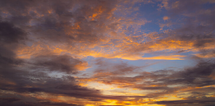 Dramatic Golden Sunset Sky with Colorful Cloudscape,Vibrant sunset sky filled with dramatic purple, orange, and golden clouds illuminated by the evening sun, creating a majestic atmospheric natural.