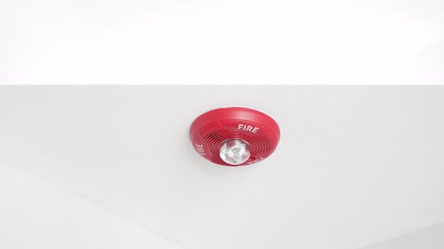 Horizontal video of Flashing fire alarm detector mounted on a white ceiling during a fire emergency. Blinking warning light symbolizes smoke detection, safety, emergency alert, fire protection