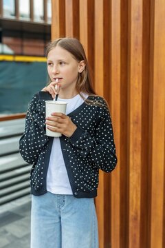 Preteen Girl Drinking Beverage with Straw at Outdoor Cafe