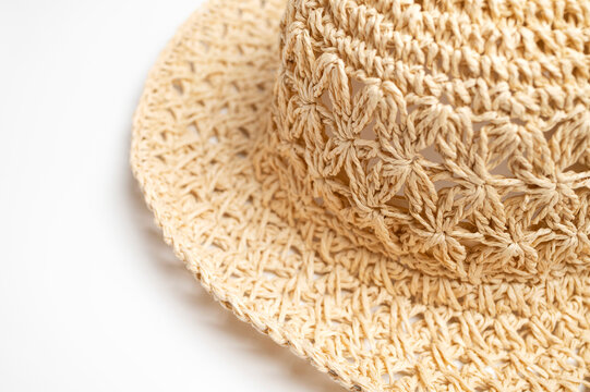 Close-up woven straw panama hat presents natural texture and warm fibers on white background. Seasonal headwear visual fits beach lifestyle campaigns, fashion marketing, product catalogs.