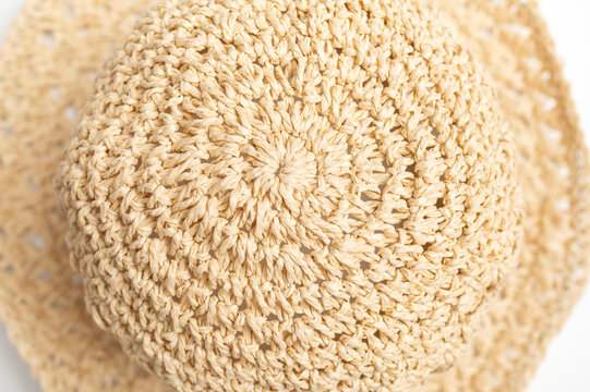 Straw panama hat fills close-up frame, showing woven fibers, wide brim, and textured crown on white background. Summer headwear suits beach fashion, travel marketing, and retail catalogs.