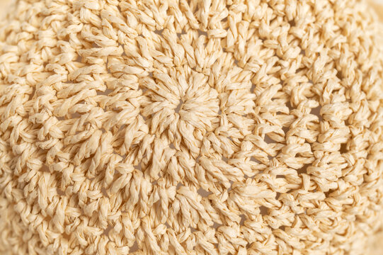 Straw weave texture shown in macro detail creates abstract natural background. Dense fibers and radial pattern offer versatile imagery for surface studies, artisan products, fashion concepts, layouts.