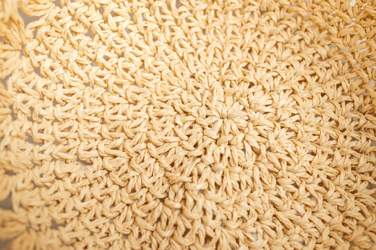Straw weave texture shown in macro detail creates abstract natural background. Dense fibers and radial pattern offer versatile imagery for surface studies, artisan products, fashion concepts, layouts.