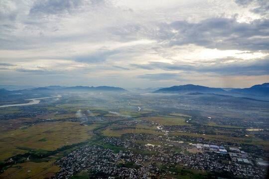 Clouds drift over the expansive green fields and houses scattered across the lowlands under the mountains in the early morning light of Northern Vietnam