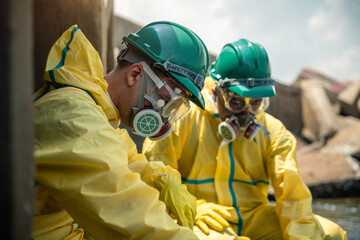Fototapeta premium Hazmat Workers Conduct Environmental Safety Inspection Near Contaminated Industrial Drainage Infrastructure While Wearing Protective Suits, Respirators, Helmets, Goggles, and Gloves