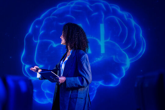 Professional woman giving a presentation in front of a digital brain illustration on a screen in an office setting